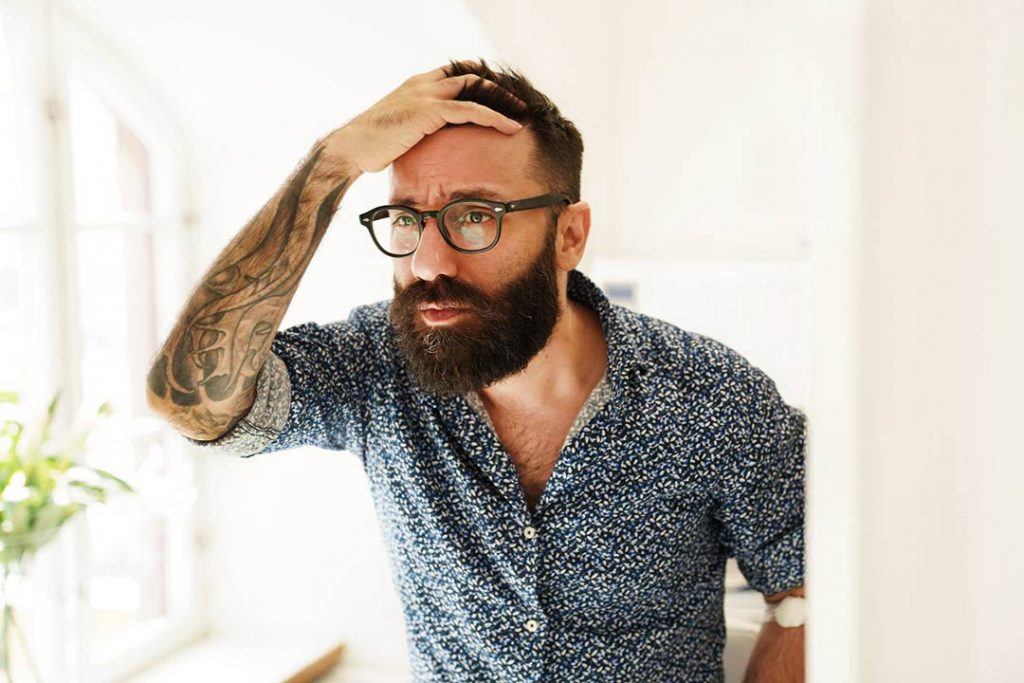 en mand med hårtab ser sig i spejlet