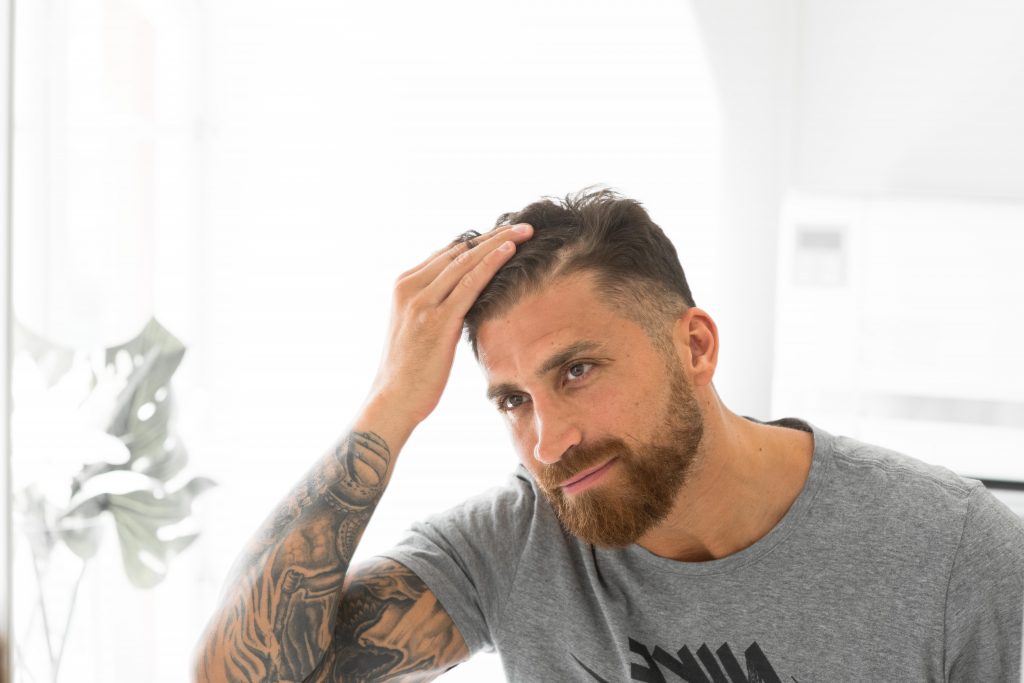 mannen tar på håret når han ser seg i speilet